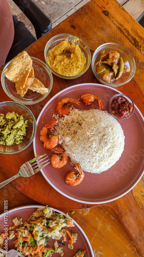 A stunning display of traditional Thai cuisine is spread out on a rustic wooden surface. Colorful plates include green curries, pad Thai, and crispy spring rolls garnished with fresh herbs.