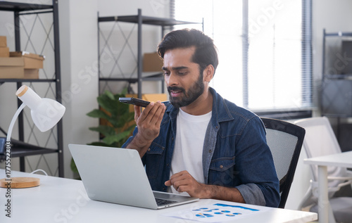 Indian man using AI voice assistant on smartphone in office, interacting with virtual assistant app for productivity, AI-powered speech, and smart technology.