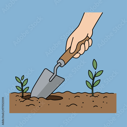 A hand uses a trowel to dig a hole in the soil next to a small plant.