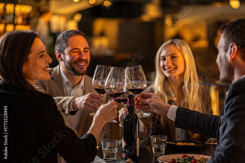 Friends toasting with wine glasses at a restaurant, celebrating a special occasion