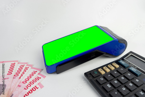 Electronic Data Capture (EDC) machines  with green screen and calculator with Indonesian money, finance technology concept