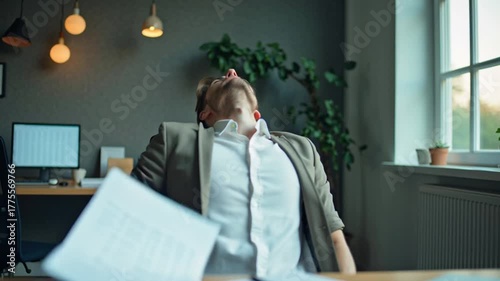 Young businessman experiencing intense stress and pressure while working late in a modern office setting, hands on head