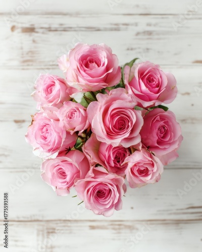 Bouquet of pink roses on a white wooden background from top view, elegant romantic and detailed with soft natural light.