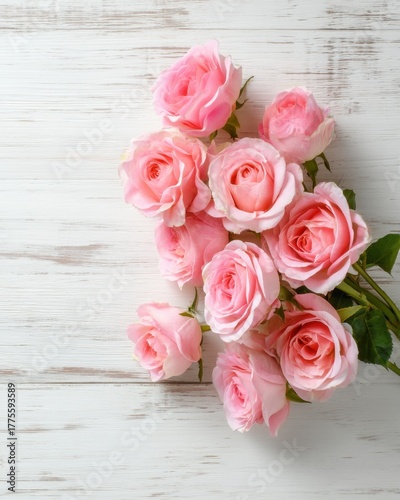 Bouquet of pink roses on a white wooden background from top view, elegant romantic and detailed with soft natural light.