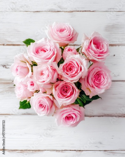 Bouquet of pink roses on a white wooden background from top view, elegant romantic and detailed with soft natural light.
