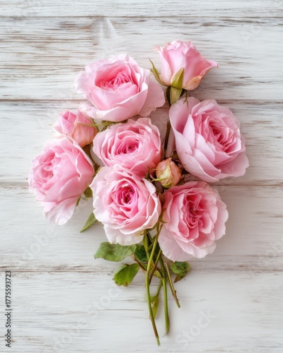 Bouquet of pink roses on a white wooden background from top view, elegant romantic and detailed with soft natural light.