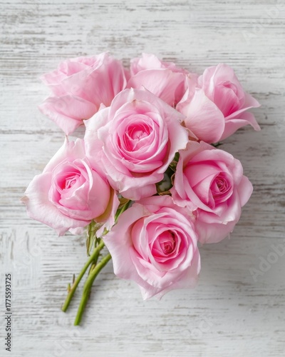 Bouquet of pink roses on a white wooden background from top view, elegant romantic and detailed with soft natural light.