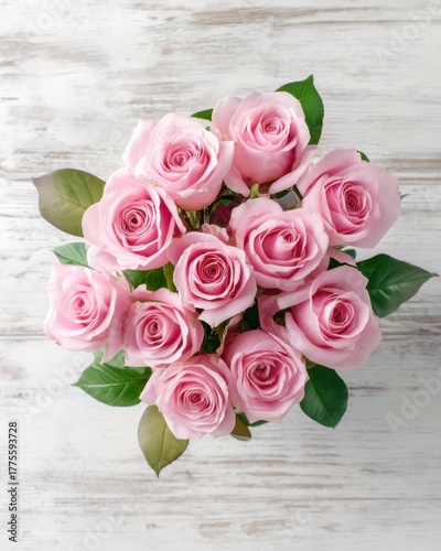 Bouquet of pink roses on a white wooden background from top view, elegant romantic and detailed with soft natural light.