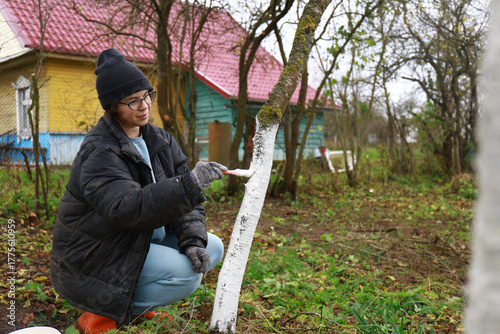 a girl is whitewashing trees	