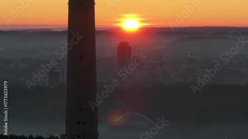 Rising sun above foggy city, TV tower passing, aerial view, first glimpse, golden hour, atmospheric