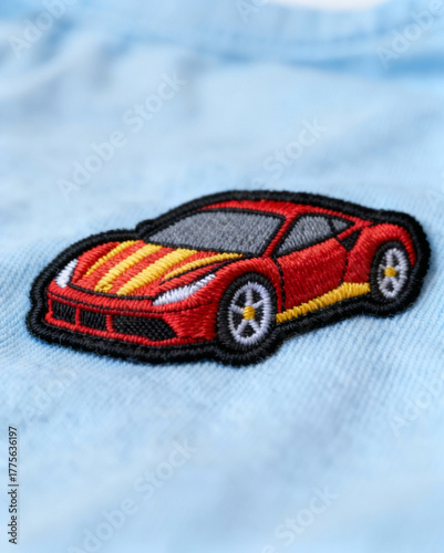 A red and yellow car is embroidered onto a blue shirt