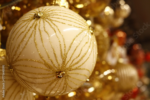 Boule de noël de couleur beige et or ronde portant des incrustations de perles dorées, de paillettes et de dorures