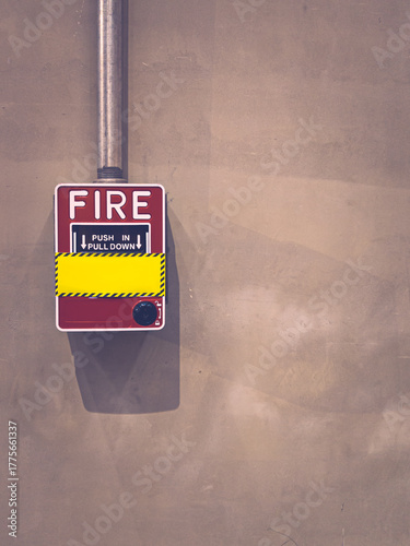 Red fire alarm on concrete wall in modern industrial interior.