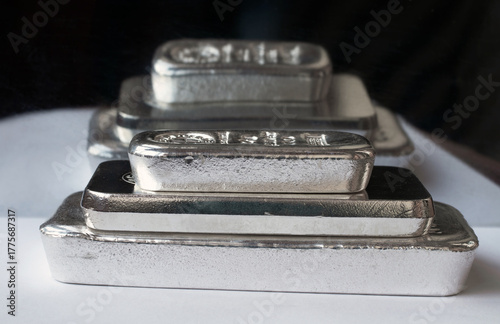 Stack of cast silver bars of different weight on a dark background. Selective focus.
