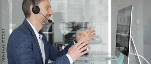 Man in headset talking during online video call, working in office, consulting remote customers, providing technical support. Business people concept