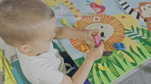 Toddler boy playing with colorful modeling clay