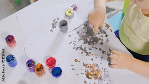 Little child finger painting on paper at the table