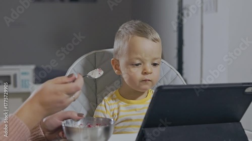 Distracted toddler watching tablet while eating