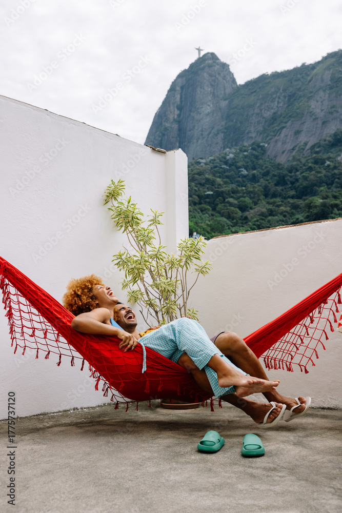 Fototapeta premium Couple relaxing in a hammock on a terrace with view of Corcovado mountain