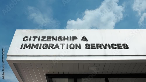 Citizenship and Immigration Services word sign displayed on the official government facade beneath a clear blue sky, signifying a facility for naturalization and immigration processing