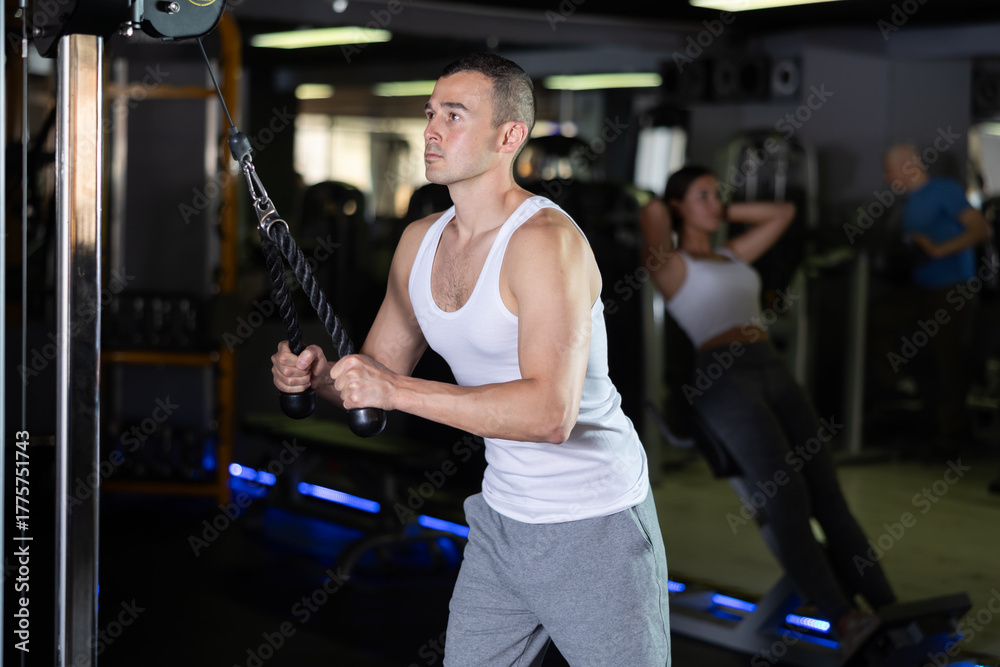 Fototapeta premium Man in sportswear training on rope loop simulator in gym