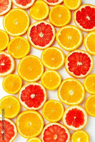 Bright top view pattern of fresh orange and grapefruit slices on a white background. Vibrant citrus texture