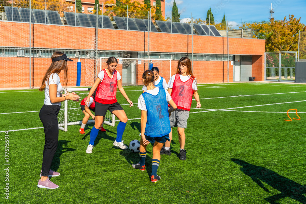 Obraz premium Coach training youth girls soccer team on field