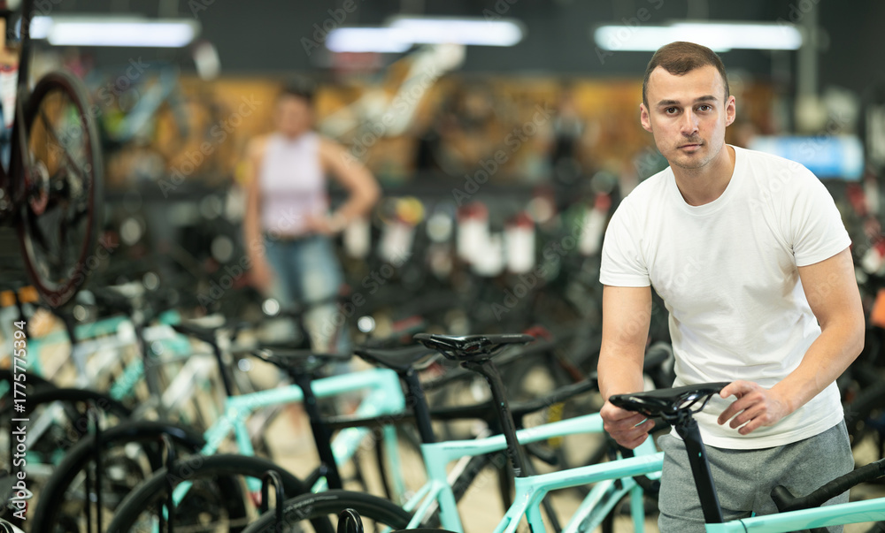 Obraz premium Young man buyer chooses bicycle in sports store