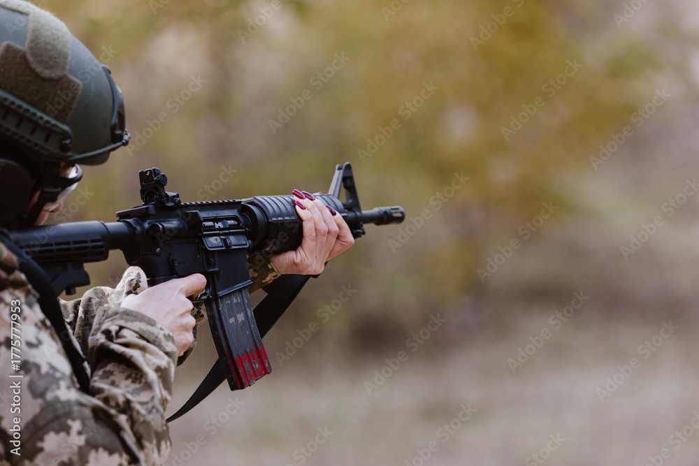 Fototapeta premium A woman in camouflage aims a rifle.