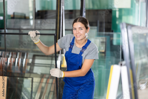 Slika na platnu Experienced female glazier controlling quality of sheet glass in workroom