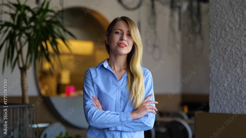 Fototapeta premium Beautiful young business lady looking at camera and smiling while standing indoors. Portrait of joyful pretty woman in restaurant. Successful entrepreneur. Positive emotions