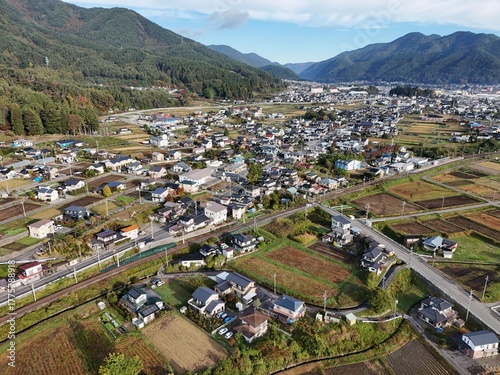 A city with a train track running through the middle of it. The train track is surrounded by houses and buildings, giving the impression of a small town