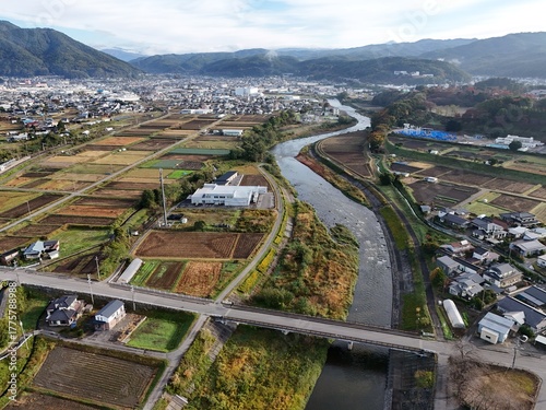 A rural area with a river running through it. The river is surrounded by farmland and houses. The sky is clear and the sun is shining