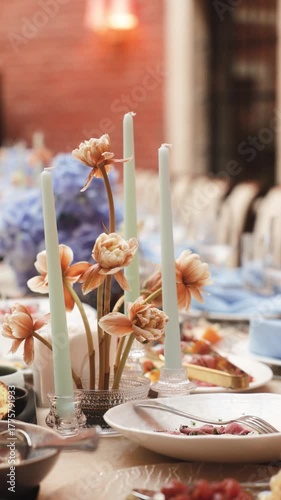 Elegant wedding table decoration with beige flowers and candles, festive dinner arrangement with blue accents and gourmet dishes, luxury event or celebration decor in soft natural light