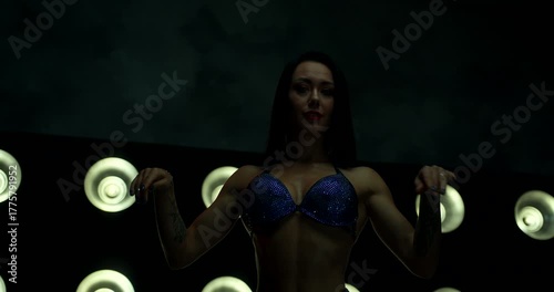 Competitor displays confident poses on stage during a fitness event. The spotlight highlights her toned physique while she showcases her skills for the audience.