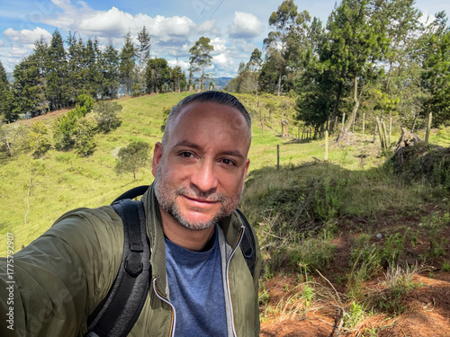 Photos POV selfie of a happy smiling man with a backpack hiking outdoors in a sunny natural landscape