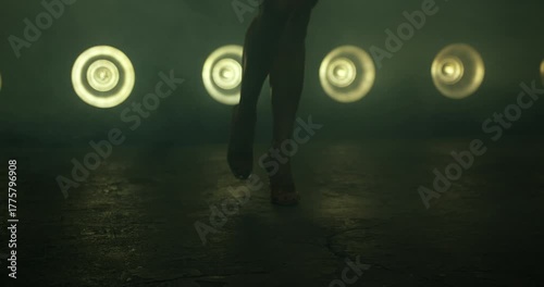 bikini fitness competitor showcases her posing technique on stage as bright lights illuminate her figure. The focused atmosphere highlights the intensity of the competition.