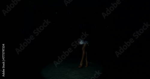 Under bright stage lights a fitness bikini model enters a beam of light showcasing her physique and confidence during a competition. The dramatic backlighting enhances the moment.