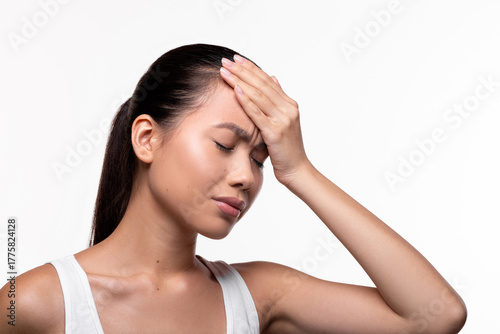 Wallpaper Mural A young Chinese woman appears unhappy as she touches her forehead with closed eyes. She is suffering from a headache in a bright white studio setting with ample copy space. Torontodigital.ca