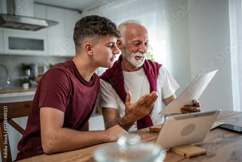 Bild auf Leinwand Grandfather teaching grandson about finances and paperwork at home