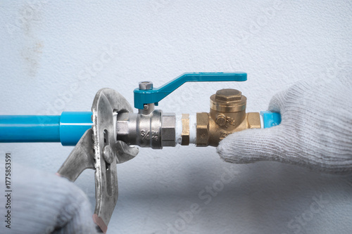 Fotografie Plumber tightening nipple fitting with pipe wrench on home water pump system