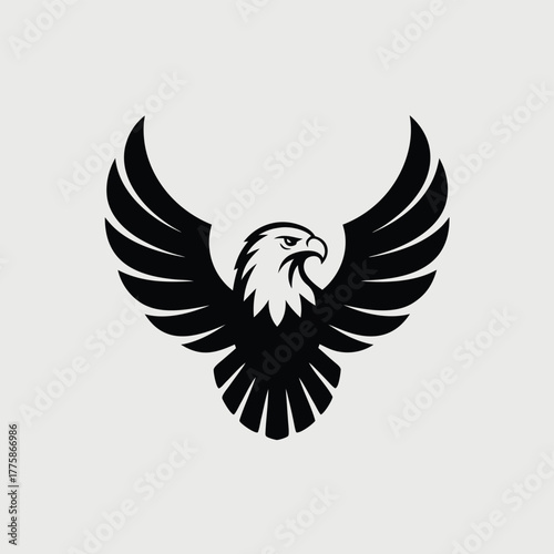 A majestic black eagle soars with its wings spread wide against a light gray backdrop, showcasing its power and grace in a striking silhouette isolated on white background