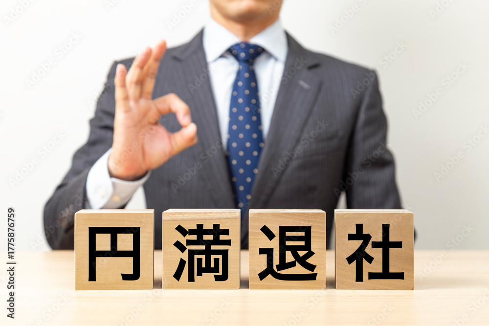 Obraz premium 「円満退社」と書かれたブロックとOKポーズをするビジネスマン
