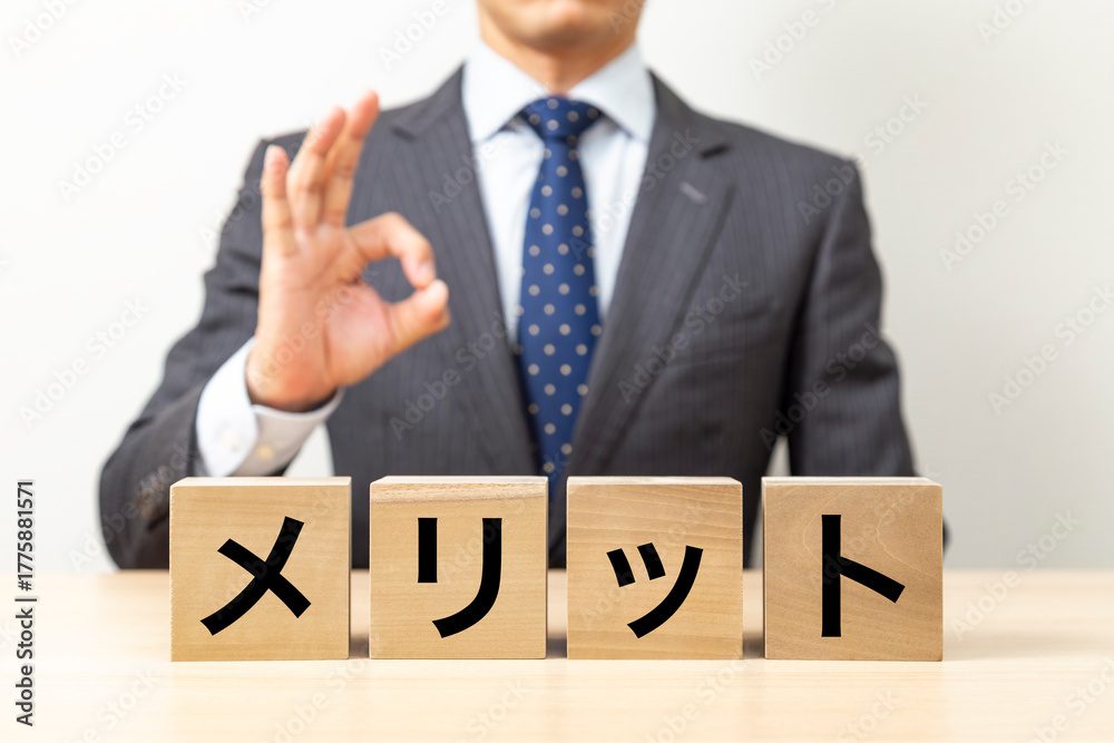 Obraz premium 「メリット」と書かれたブロックとOKポーズをするビジネスマン