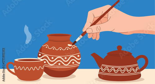 A person's hand meticulously paints a traditional terracotta pot with white patterns, while other pottery items like a cup and teapot sit nearby.