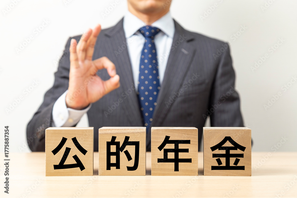 Obraz premium 「公的年金」と書かれたブロックとOKポーズをするビジネスマン