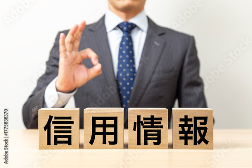 「信用情報」と書かれたブロックとOKポーズをするビジネスマン