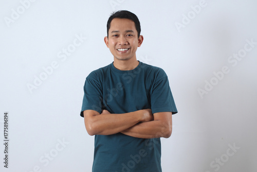 Confident Asian man smiling with arms crossed on white background.