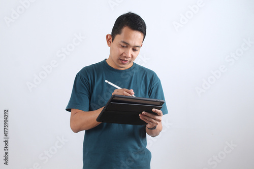 Focused Asian man working on a digital tablet with a stylus pen