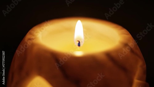 A single candle burns brightly in a dark, tranquil setting